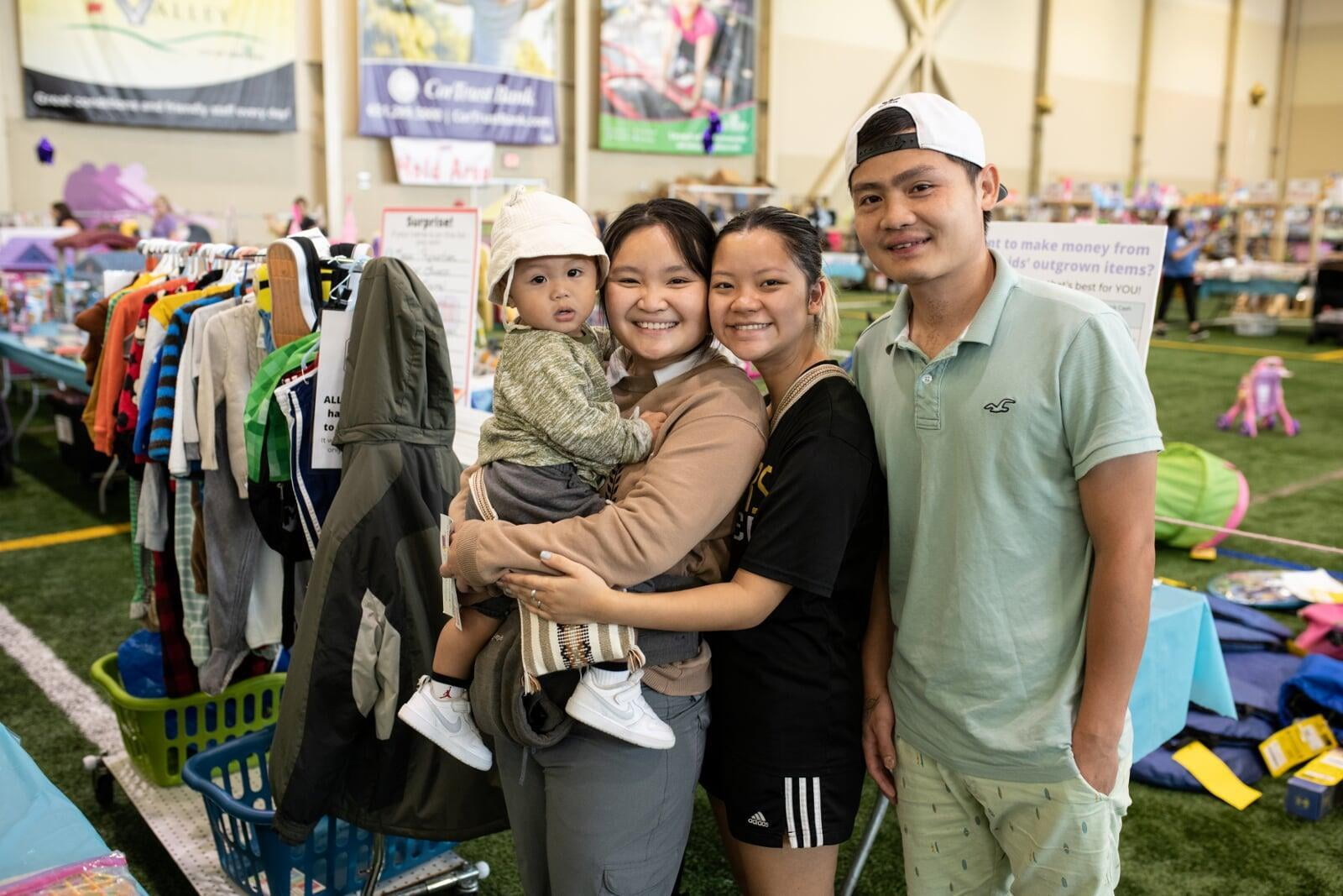 Grandmom, mom and baby in a carrier gather together and flash a smile as they shop for baby items.