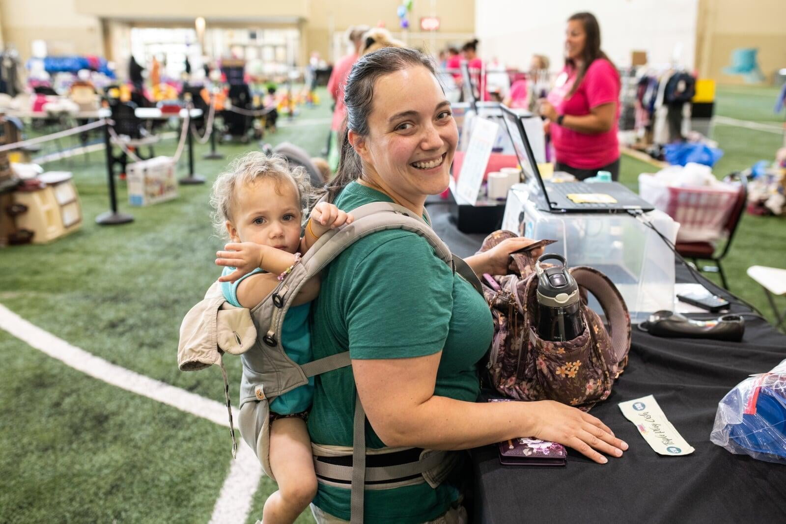 Beautiful mom holds two boys tops—one in each hand—as she shops the deals at her local sale.